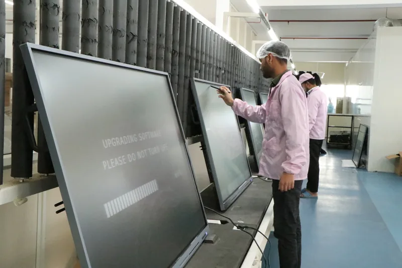 StudynLearn technician running software and touch calibration burn-in tests on an IFP production line